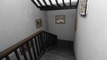 Una escalera con barandilla de madera y balaustrada negra, que conduce a un rellano con dos obras de arte enmarcadas en las paredes.