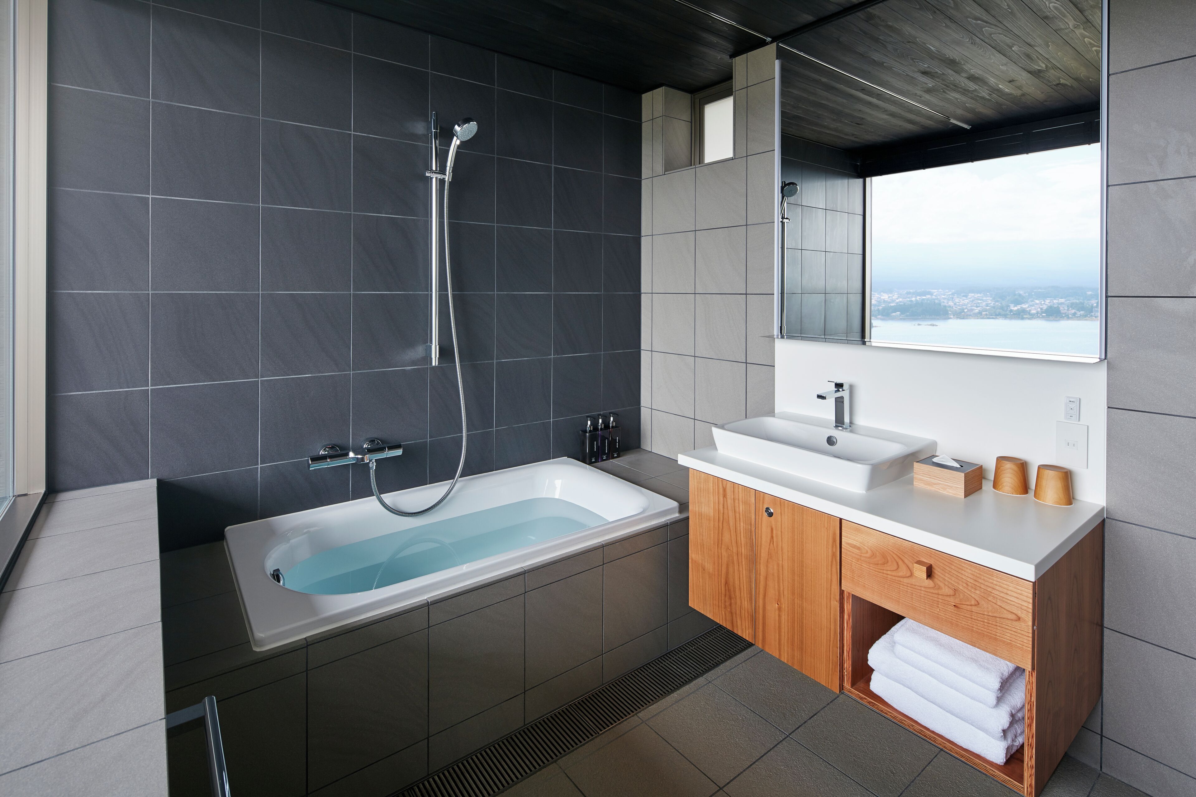 A modern bathroom with a bathtub, a shower, a sink, and a vanity with a mirror.