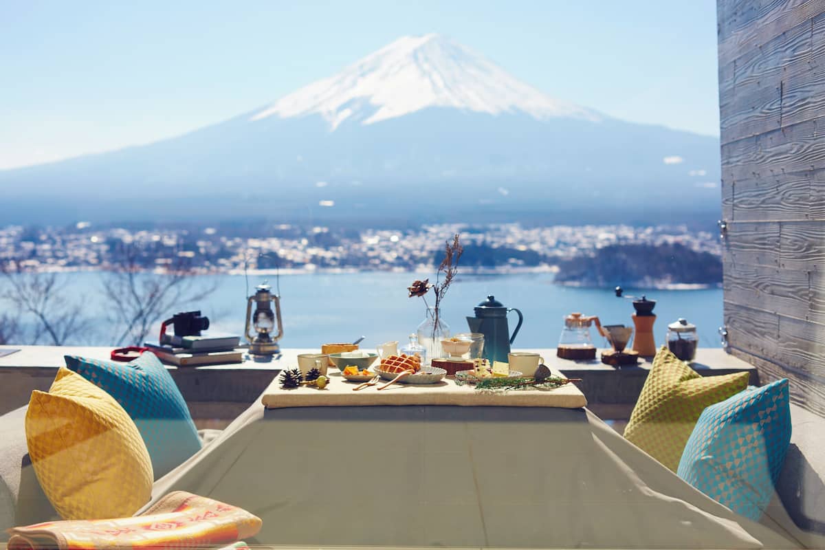 A table set with various items, a view of a mountain, and a body of water.