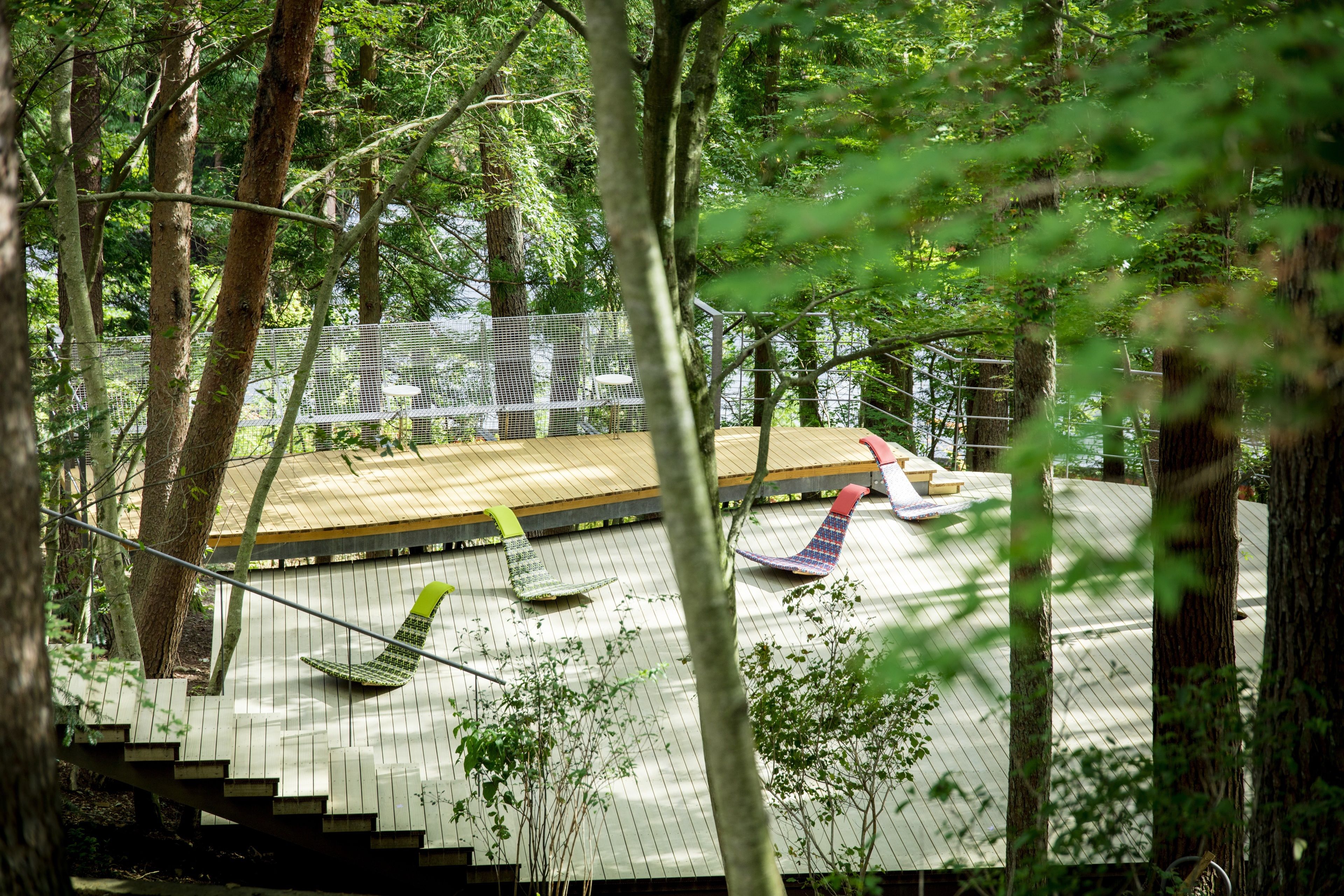 A wooden deck with a metal fence, surrounded by trees.