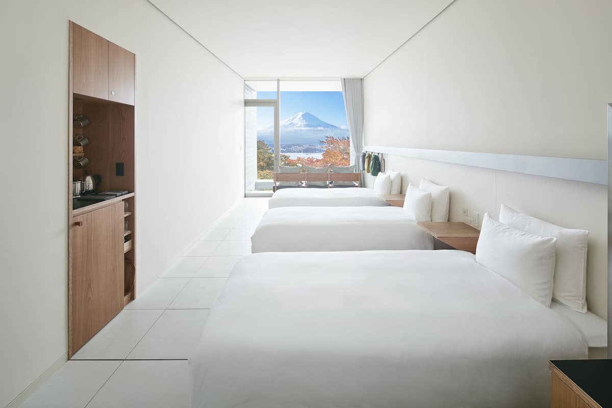 A modern hotel room with a large bed, a wooden wardrobe, and a view of a mountain.