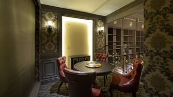 A room with a round table, leather chairs, a bookshelf, and patterned wallpaper.