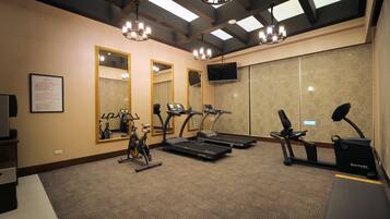 A gym with treadmills, stationary bikes, and a bench.