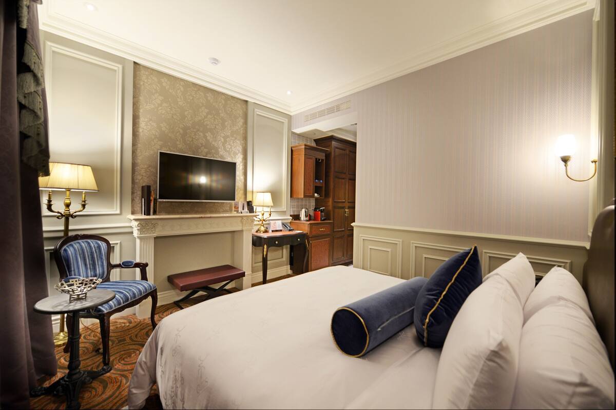A hotel room with a bed, a desk, a chair, a television, and a bathroom.