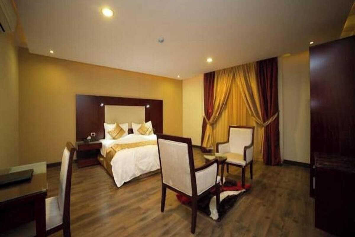Ein Hotelzimmer mit einem Bett, zwei Stühlen, einem Schreibtisch und einem Kleiderschrank.