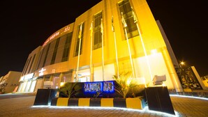 A hotel with a prominent entrance, large windows, and a well-lit facade at night. - Raoum Inn Hotel Apartments- Buraydah (Buraydah)