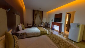 Une chambre d’hôtel avec deux lits, un bureau, une chaise, une télévision et un réfrigérateur.