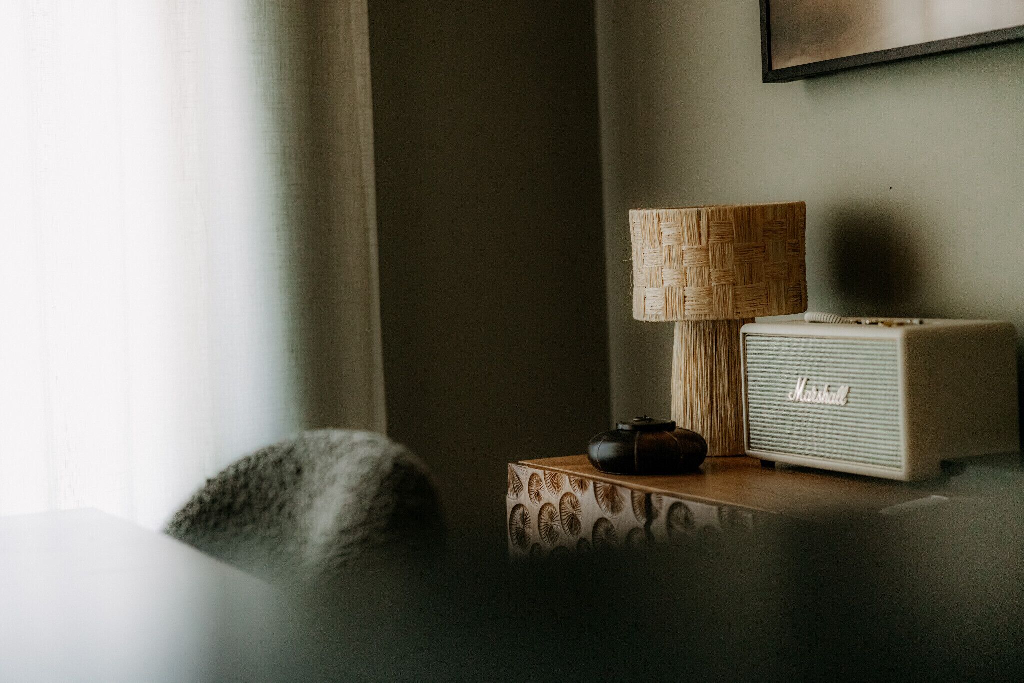 Een kamer met een lamp, een speaker en een decoratieve doos op een tafel.