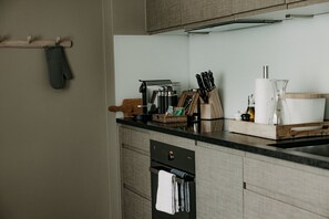 Una cocina con cafetera, cuchillos y tabla de madera en la encimera.