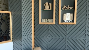 Un intérieur moderne avec des murs aux motifs géométriques, un comptoir d’accueil et deux tables rondes accompagnées de chaises.