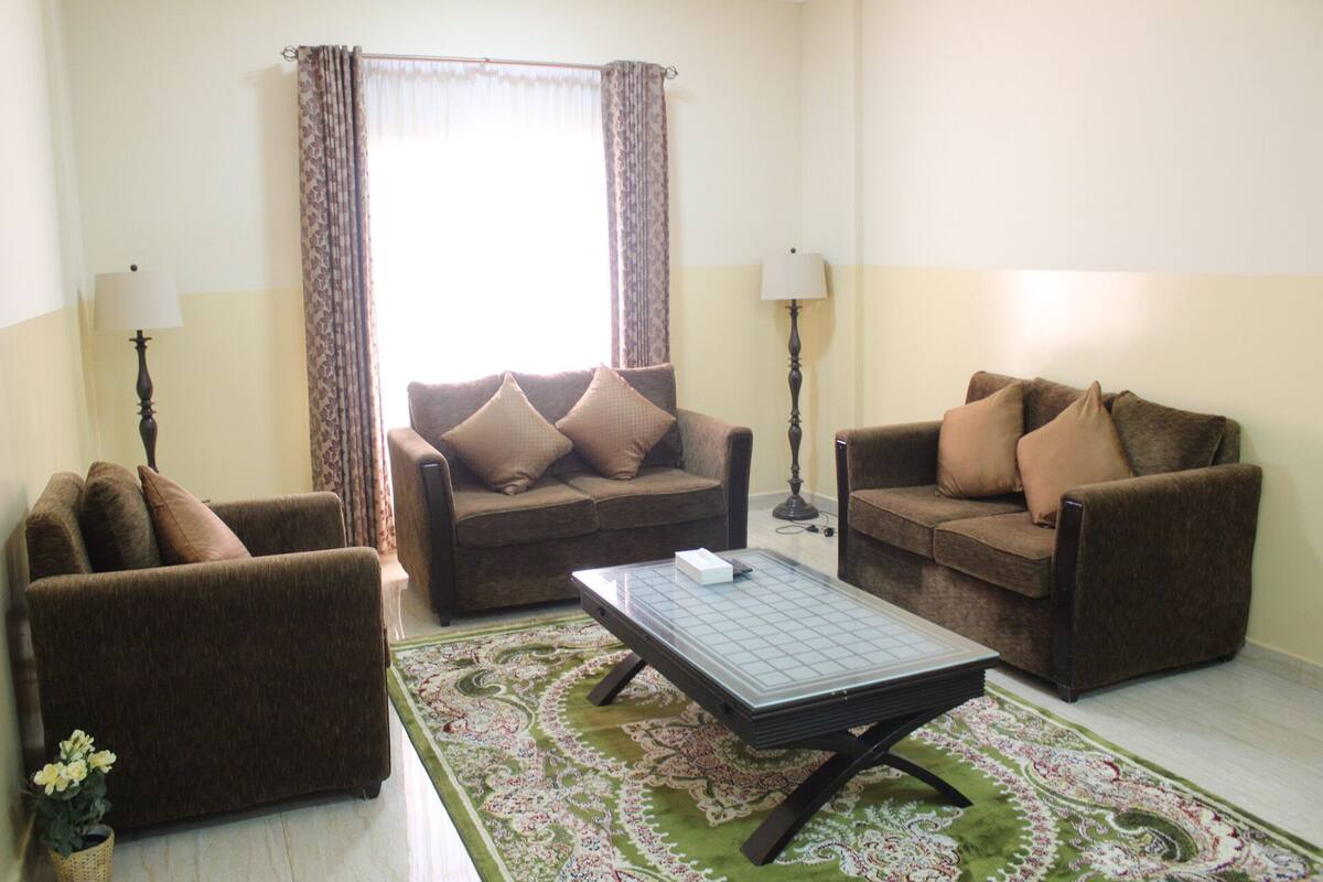 A living room with two sofas, a coffee table, and a patterned rug.