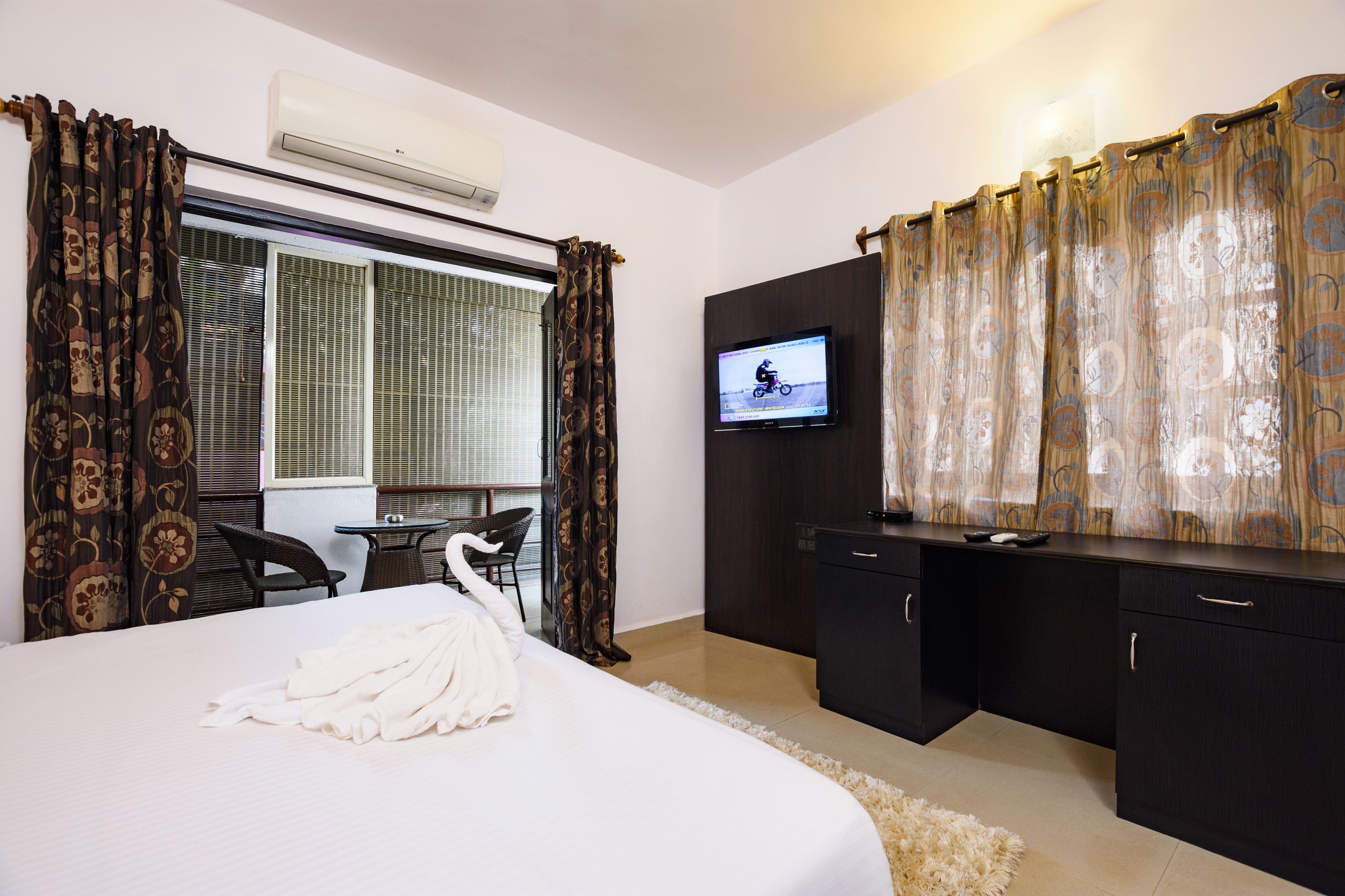 Une chambre d’hôtel avec un lit, une télévision, un bureau et une chaise.
