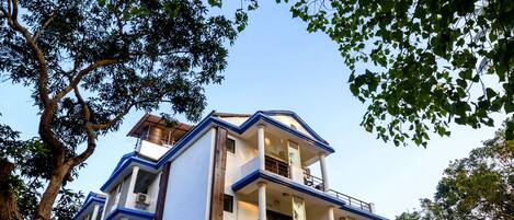 A multi-story building with a flat roof, large windows, and a balcony on the upper floors.