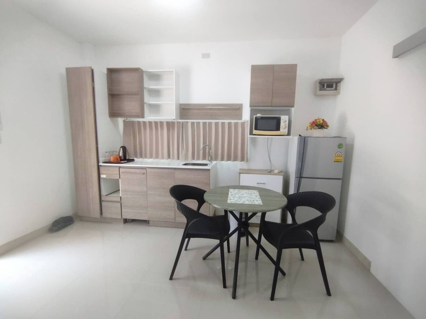 Une cuisine compacte avec un coin repas, comprenant un four à micro-ondes, un réfrigérateur et une petite table avec des chaises.