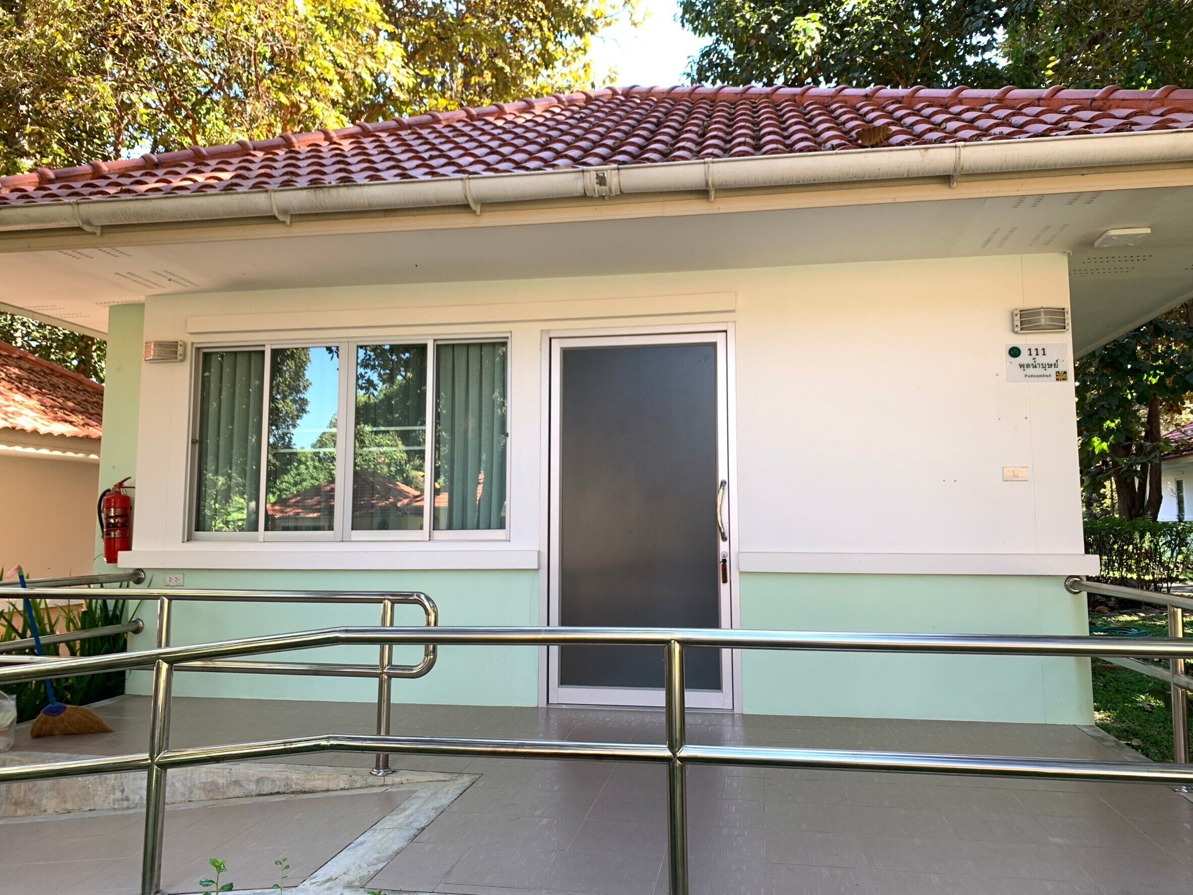 Un edificio con techo de tejas, una puerta y ventanas con cortinas.