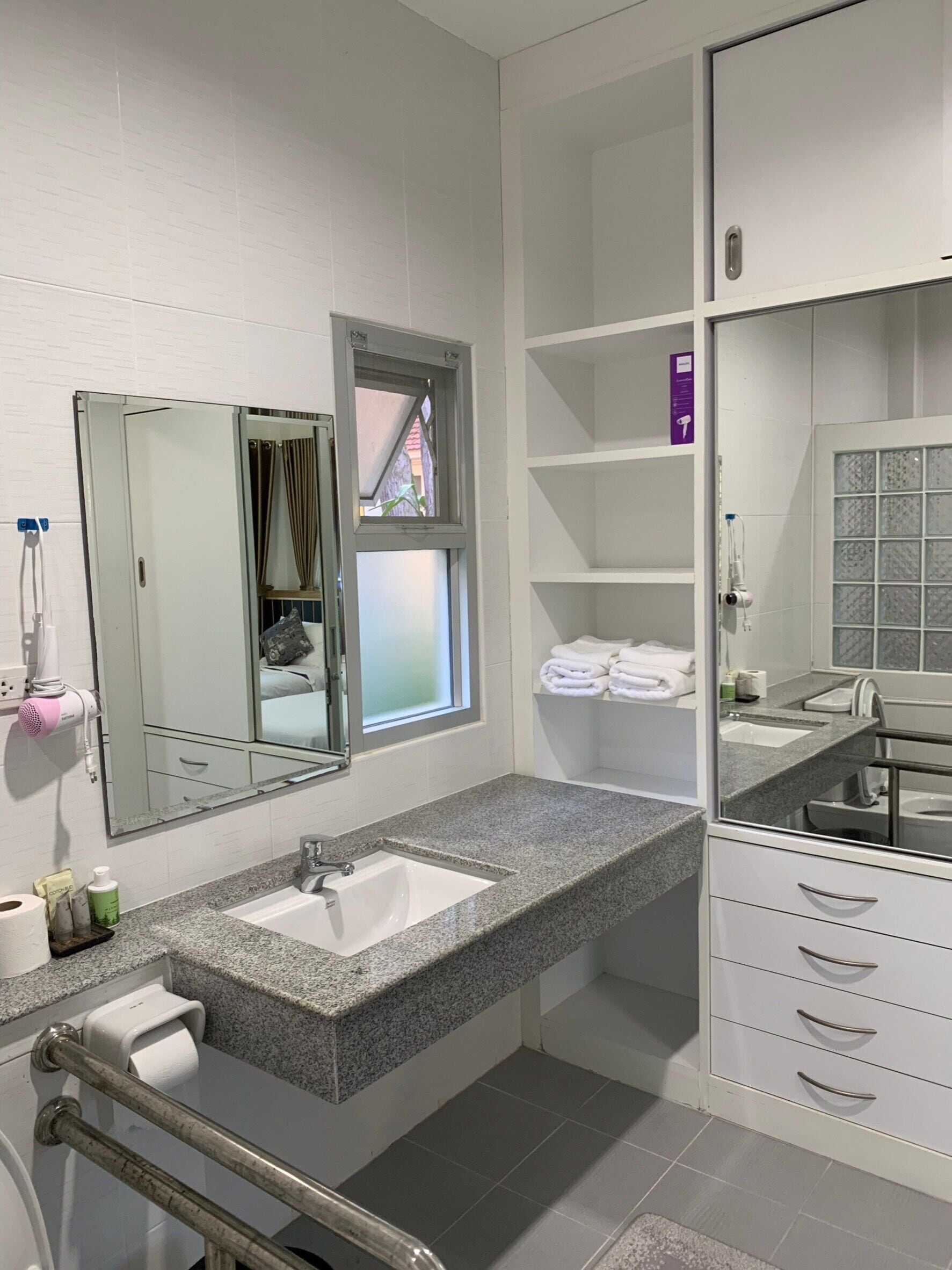 A modern bathroom with a large mirror, two sinks, and a walk-in shower.