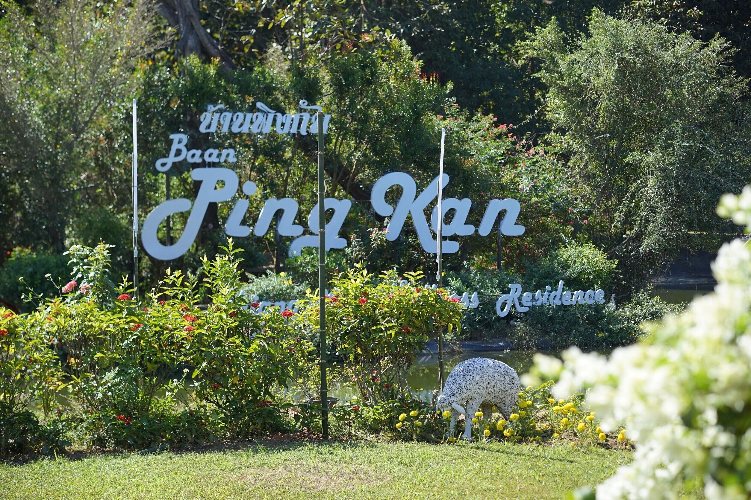 A sign for 'Baan Ping Kan Residence' with a garden in the background.
