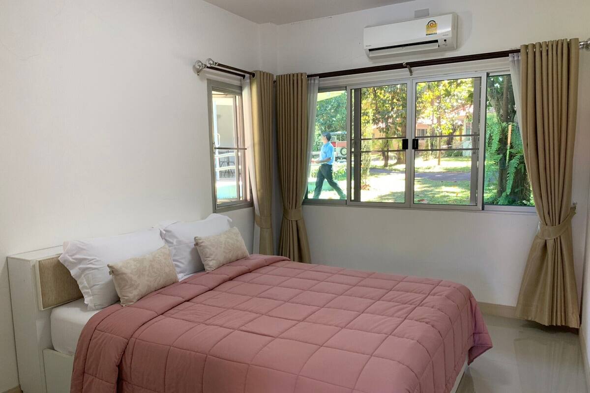 A bedroom with a bed, a window, and an air conditioning unit.