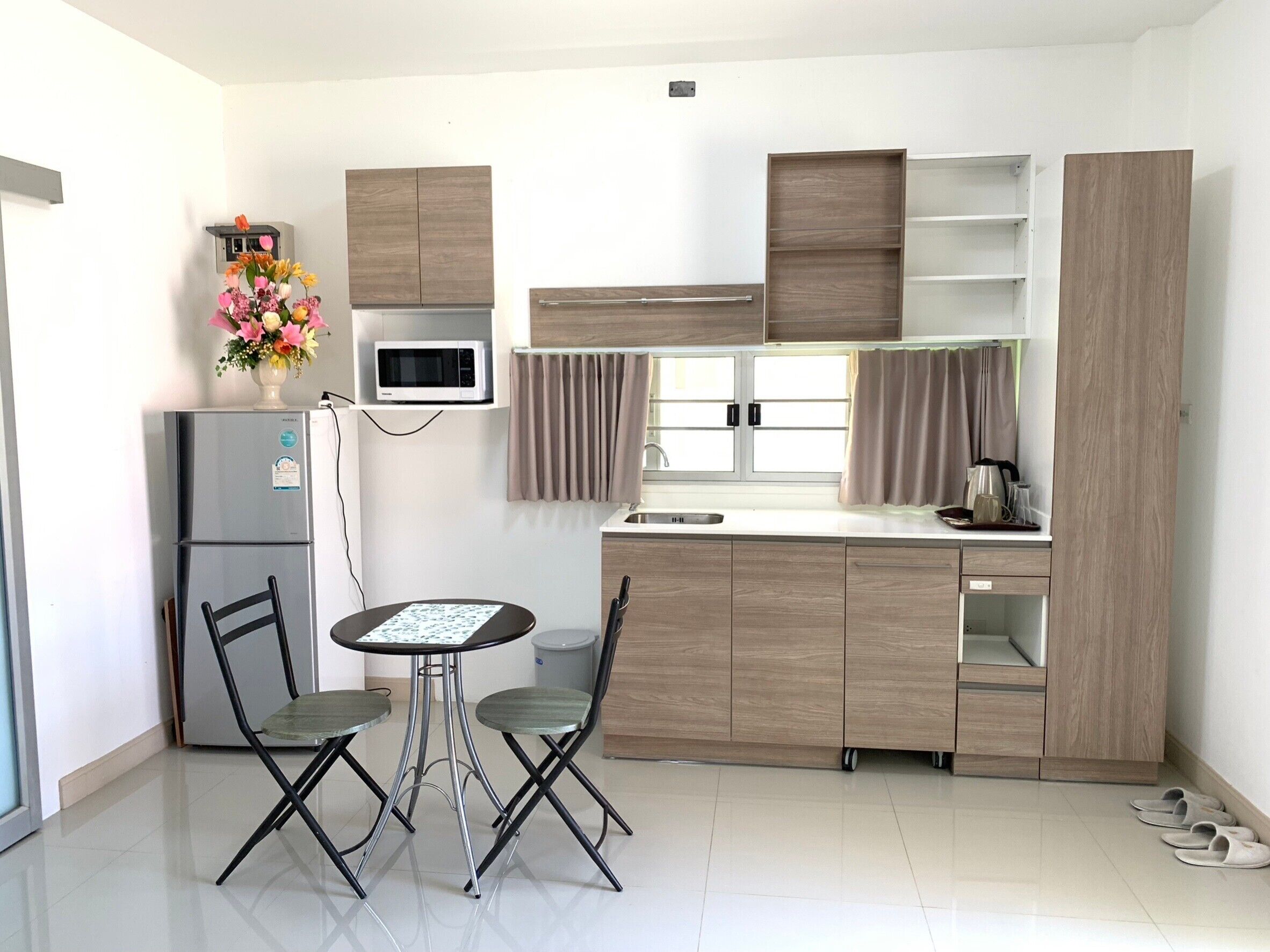 A compact kitchen with a refrigerator, microwave, and a small dining table with chairs.