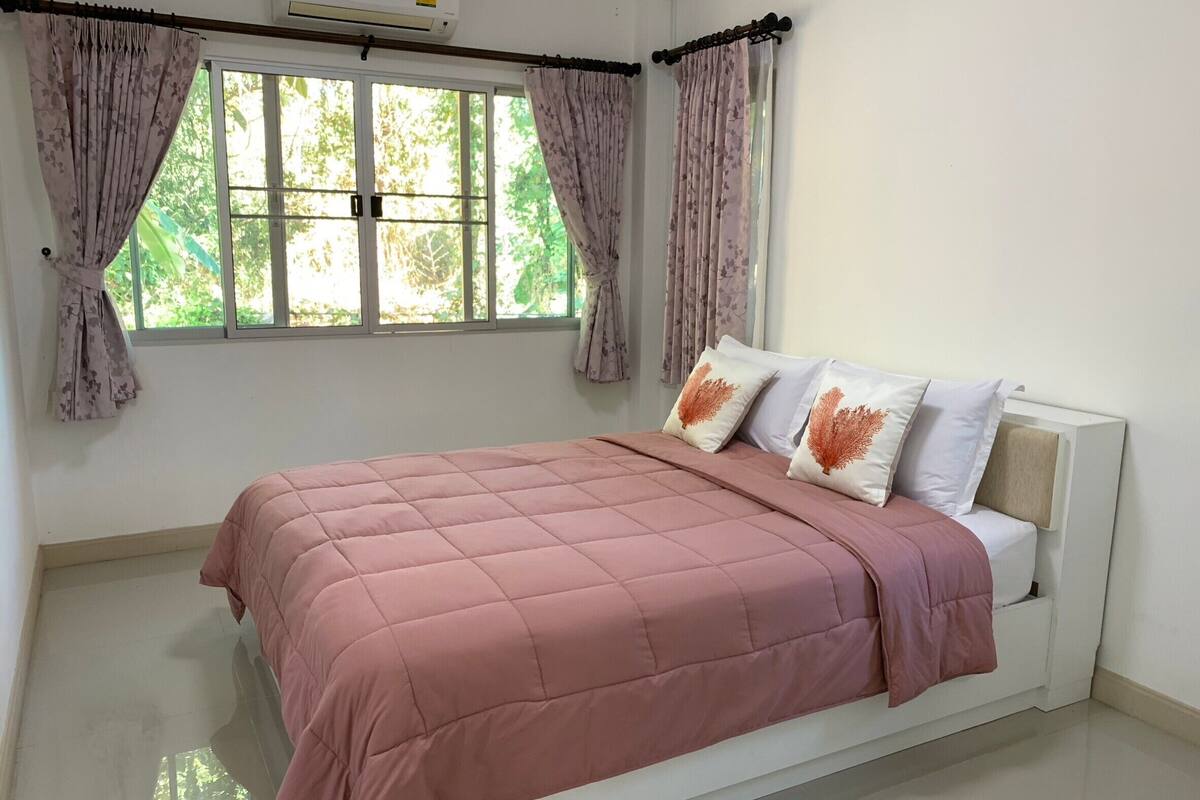 A bedroom with a bed, curtains, and an air conditioning unit.