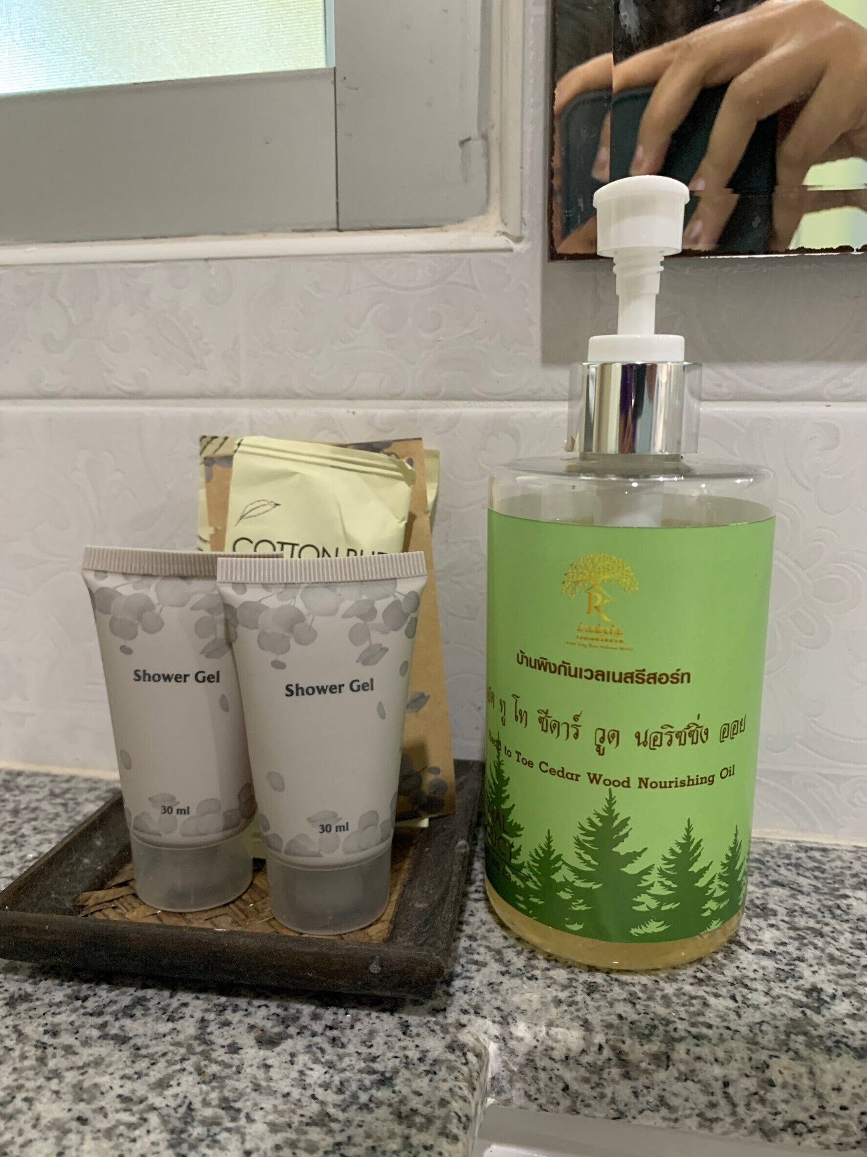 A bathroom counter with two shower gel tubes, a bottle of nourishing oil, and a tissue box.