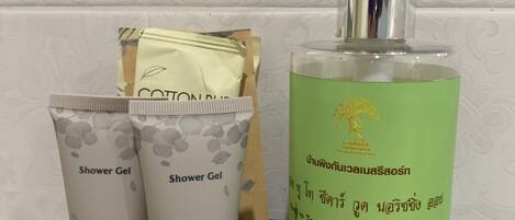 A bathroom counter with two shower gel tubes, a bottle of nourishing oil, and a tissue box.