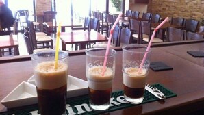 Tres vasos de una bebida con pajitas sobre un posavasos con la palabra "Heineken" a la vista.