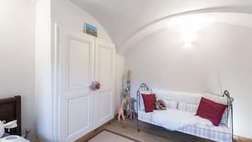 A bedroom with a white sofa, a bed with a wooden headboard, a wardrobe, and a curved ceiling.