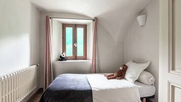 A bedroom with a bed, a window with curtains, a teddy bear, and a panda plush toy.
