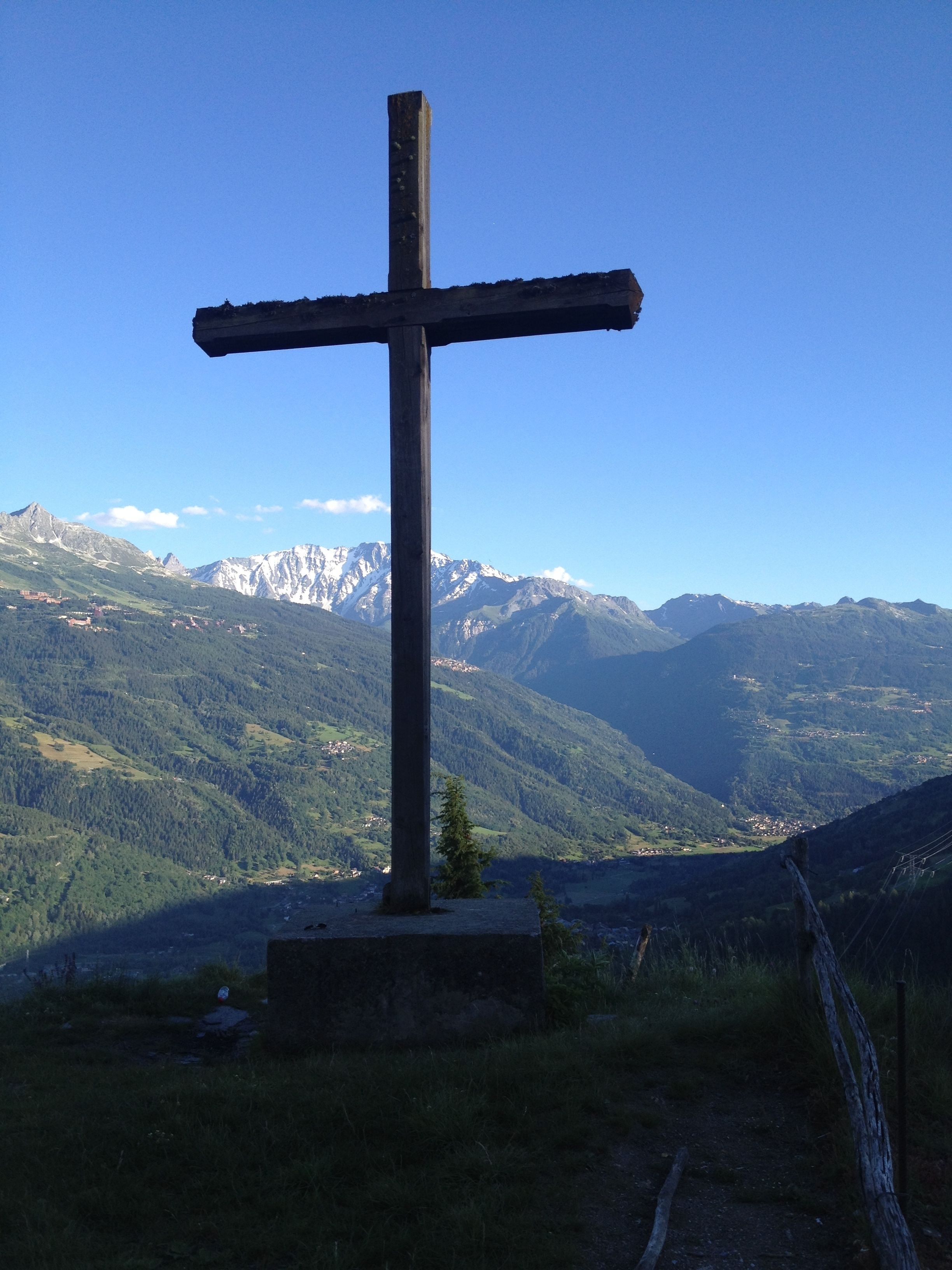 A cross on a hill with a mountain backdrop.