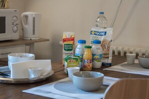 Une table en bois dressée pour le petit-déjeuner, avec divers aliments et ustensiles de cuisine.