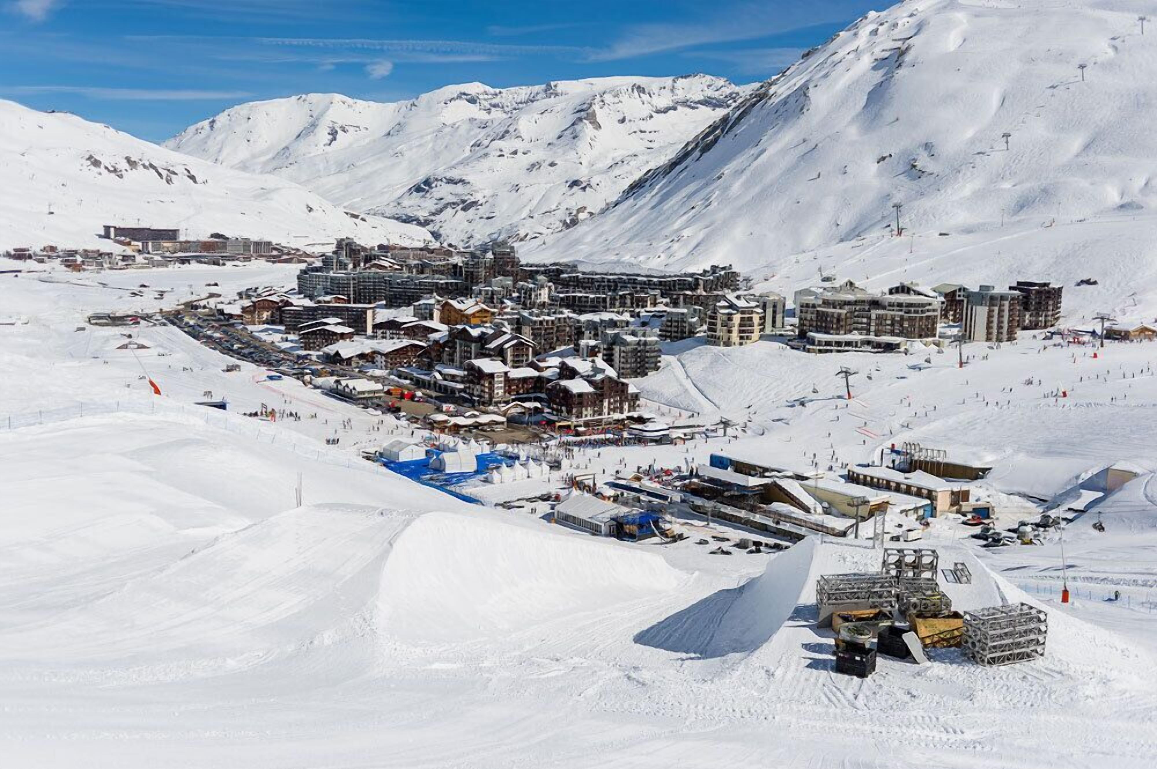 A snow-covered mountain resort with multiple buildings, ski slopes, and a ski lift.