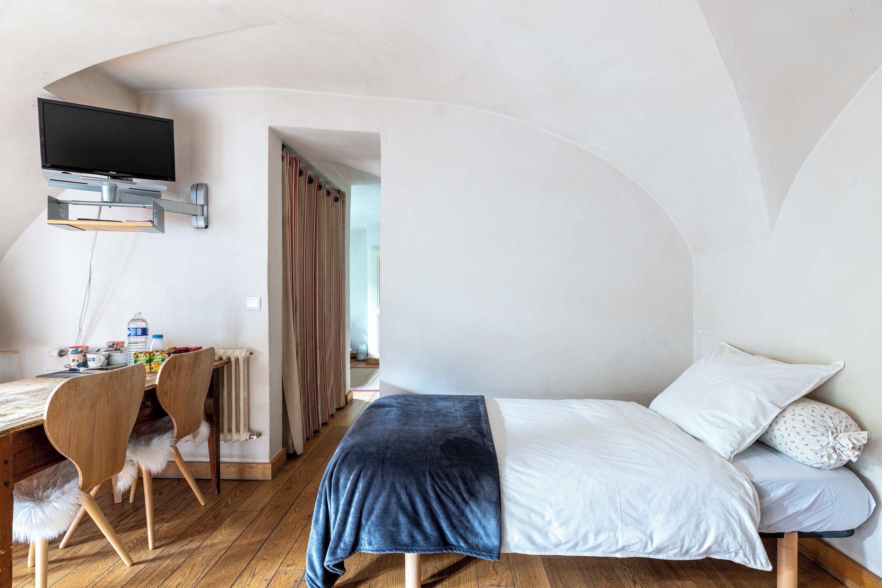 Une chambre à coucher comprenant un lit, un bureau et un téléviseur fixé au mur.