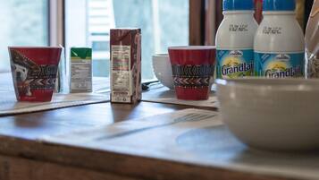 A kitchen counter with a carton of milk, two cups, and two bottles of Grandlait juice.