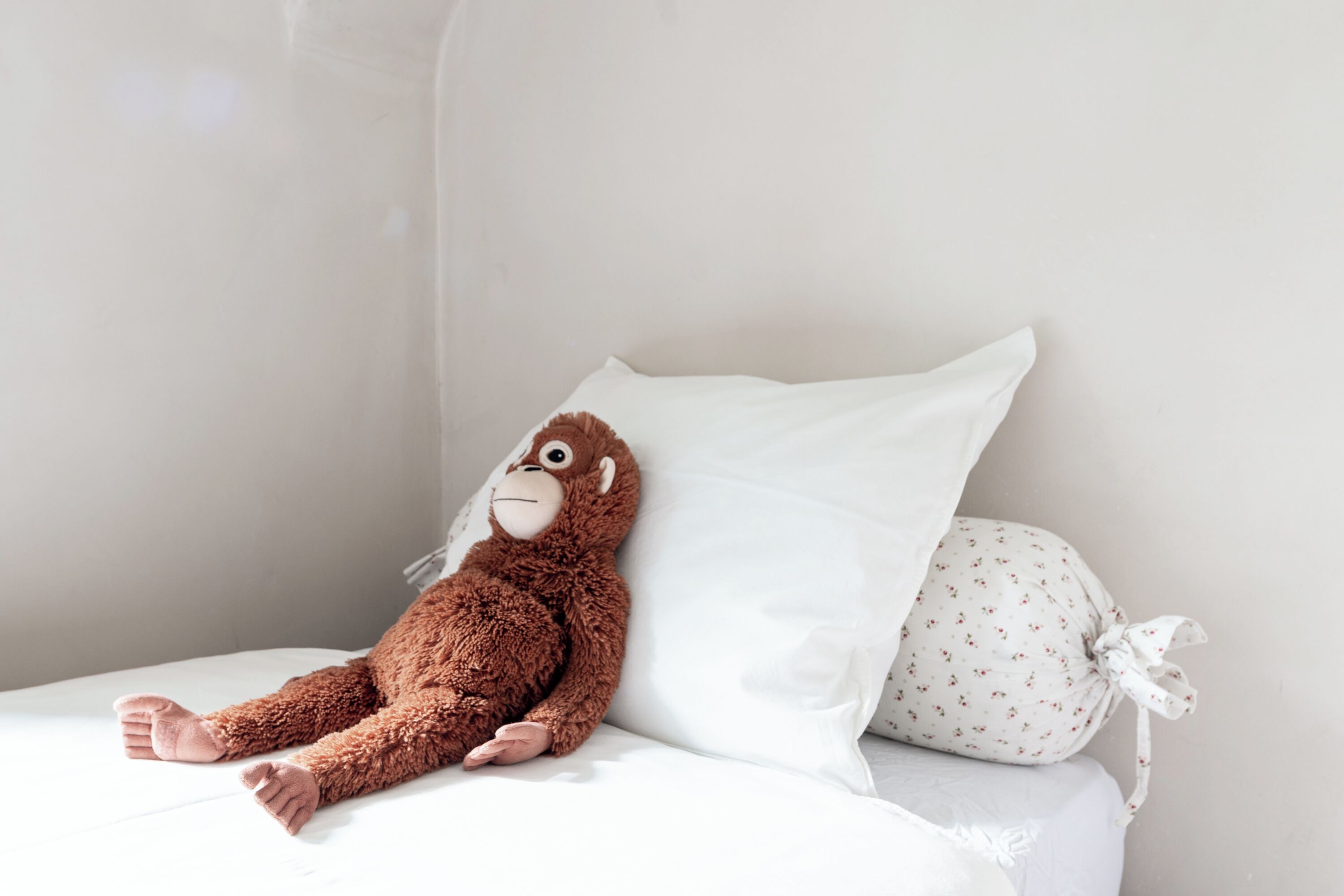 A bed with a plush toy and a pillow.