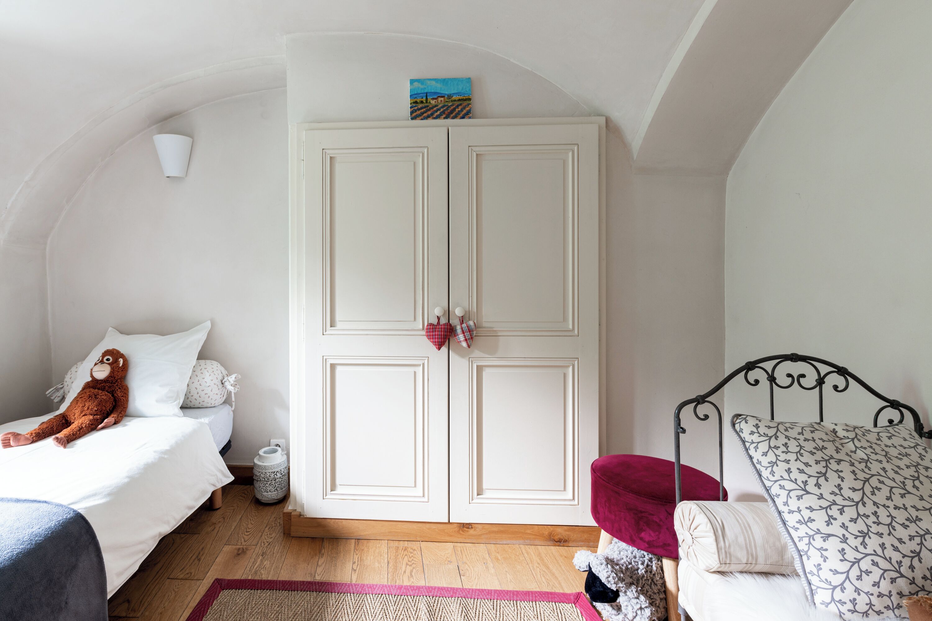 A bedroom with a bed, a wardrobe, a small table, and a chair.