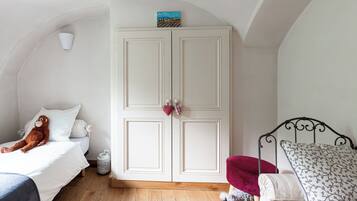 A bedroom with a bed, a wardrobe, a small table, and a chair.