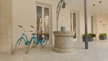 Um edifício com piso de azulejos, uma bicicleta azul e uma fonte de pedra.