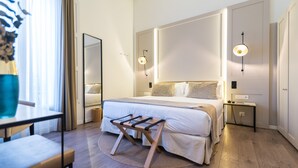 Ein modernes Hotelzimmer mit einem großen Bett, Nachttischen, einem kleinen Schreibtisch und einem Spiegel.