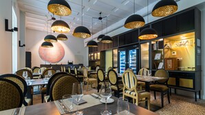 Ein Restaurant mit mehreren Tischen, Stühlen und hängenden Pendelleuchten.