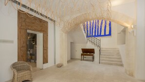 Eine geräumige Lobby mit einer Holzbank, einer Treppe mit einer blau gestreiften Wand und einem Korbstuhl.