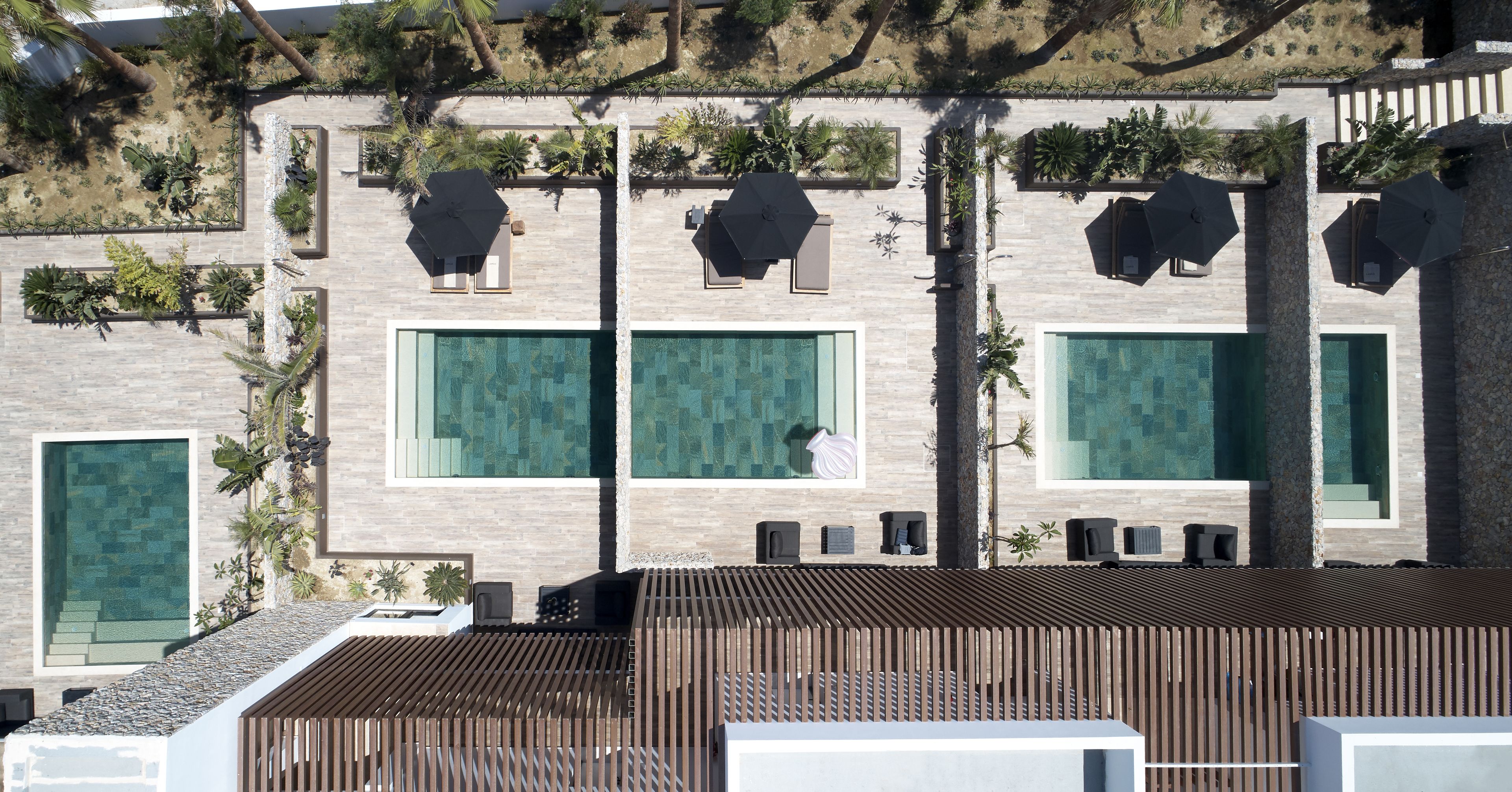 Un edificio moderno con varias piscinas, zonas de estar al aire libre y una terraza en la azotea.