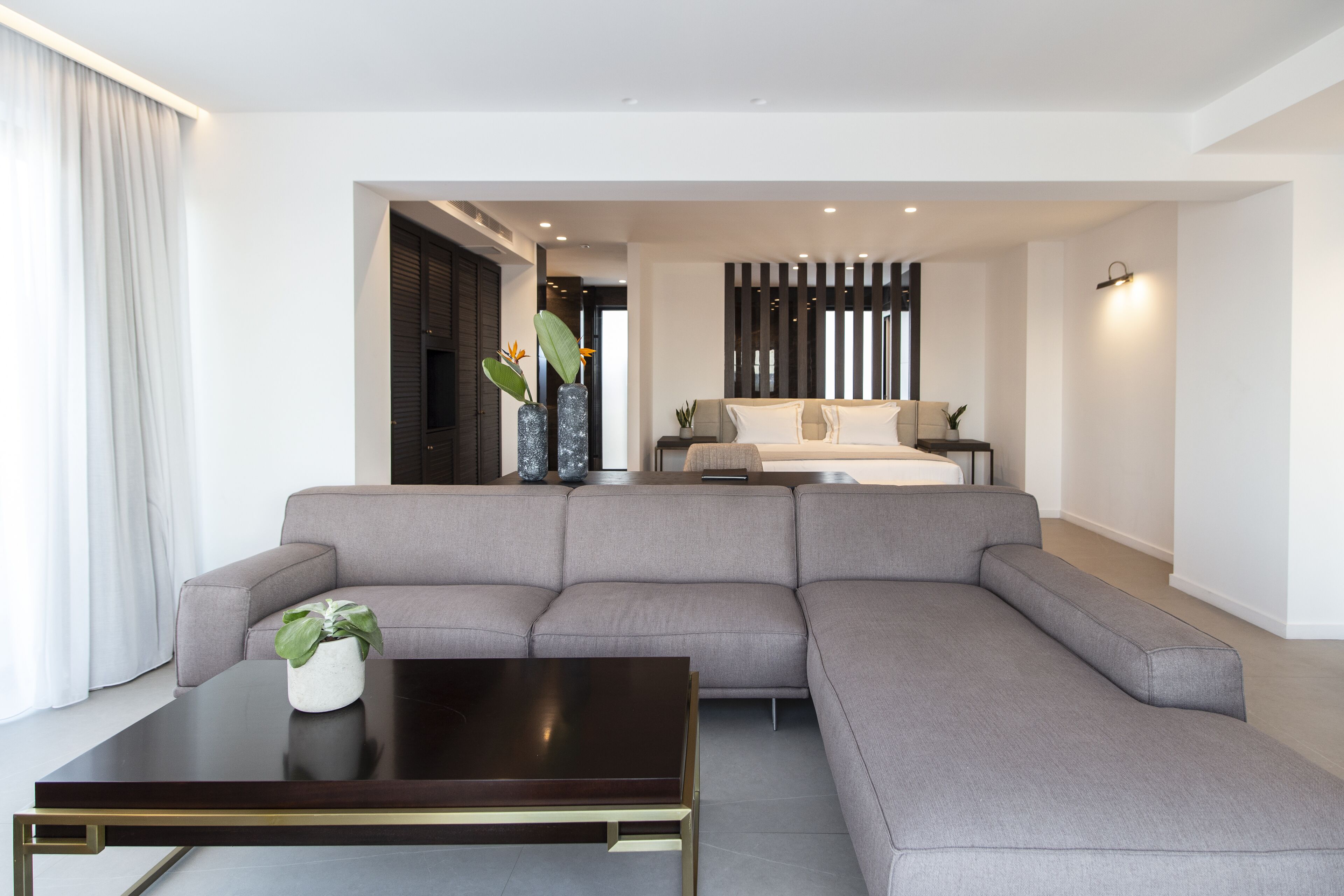 Una sala de estar moderna con un sofá seccional gris, una mesa de centro de madera oscura y una planta en maceta.