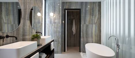 Un baño moderno con dos lavamanos, una bañera independiente y un espejo grande.