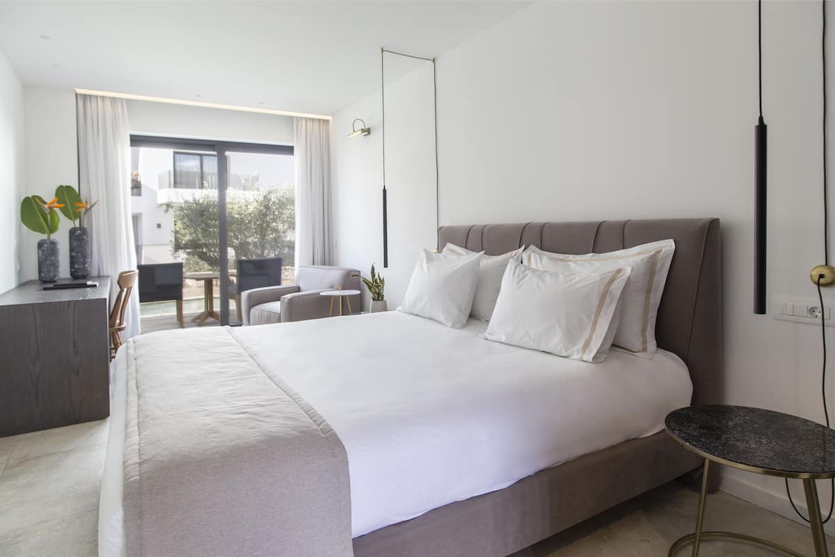 Une chambre d’hôtel moderne, dotée d’un grand lit, d’un bureau, d’une chaise et offrant une vue sur l’extérieur.