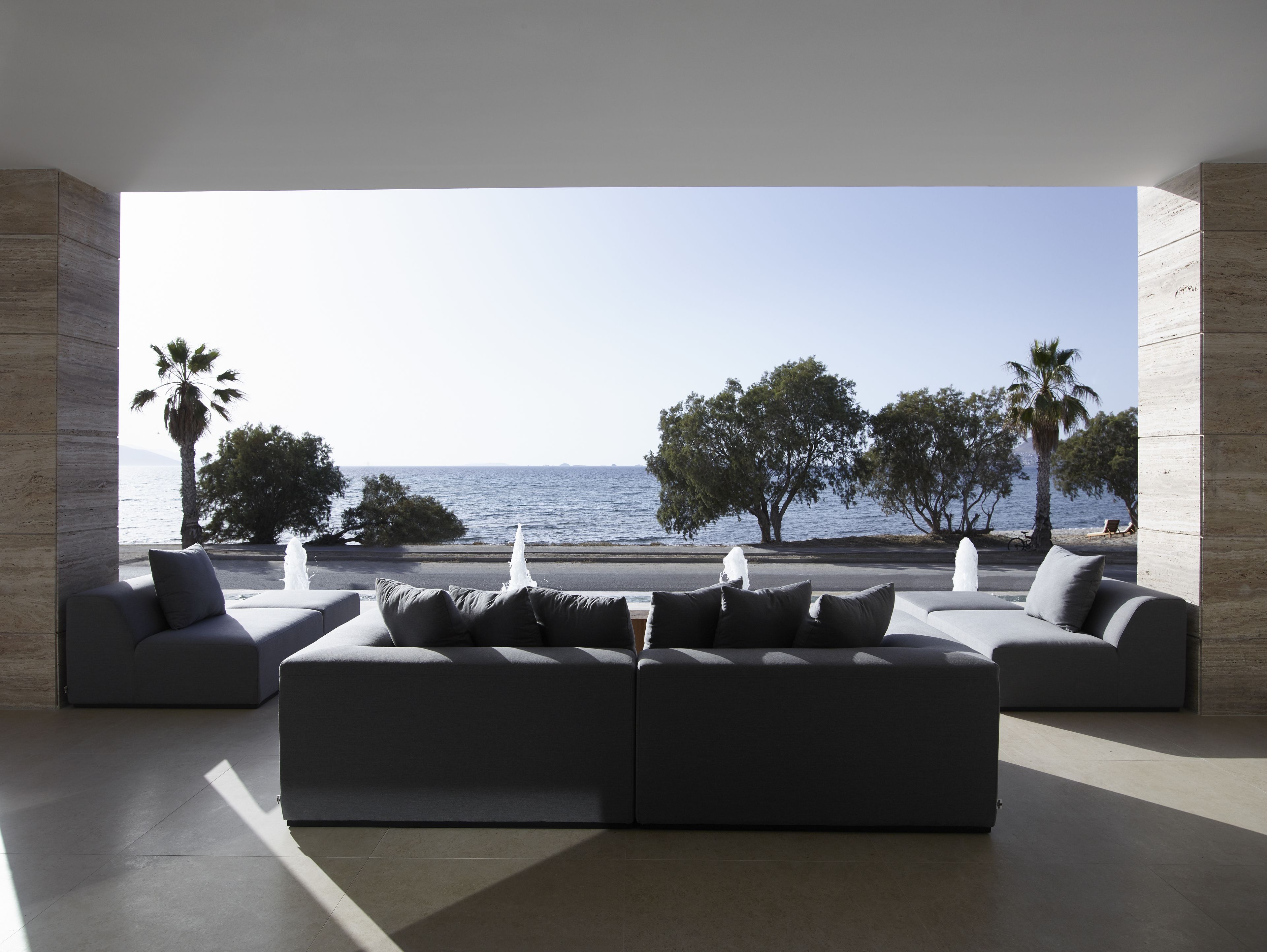 Een moderne woonkamer met een ruime modulaire bank en uitzicht op zee.