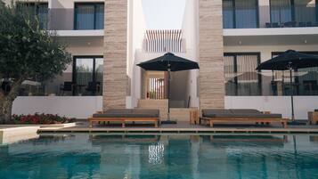 Una piscina techada, sombrillas, sillones reclinables de piscina