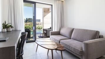A modern living room with a sofa, a dining table, and chairs. There is a sliding glass door leading to an outdoor area.