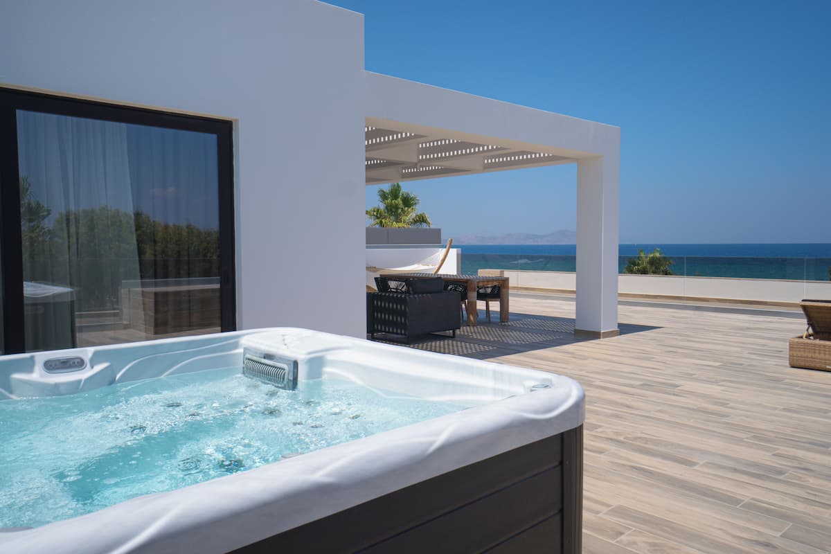 Un espace moderne aménagé à l’extérieur avec un jacuzzi, une vue sur la mer, une pergola et du mobilier d’extérieur.