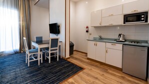 A compact hotel room with a dining area, a small kitchenette, and a flat-screen TV. - Platinum Alkhamseen Serviced Apartments (Taif)